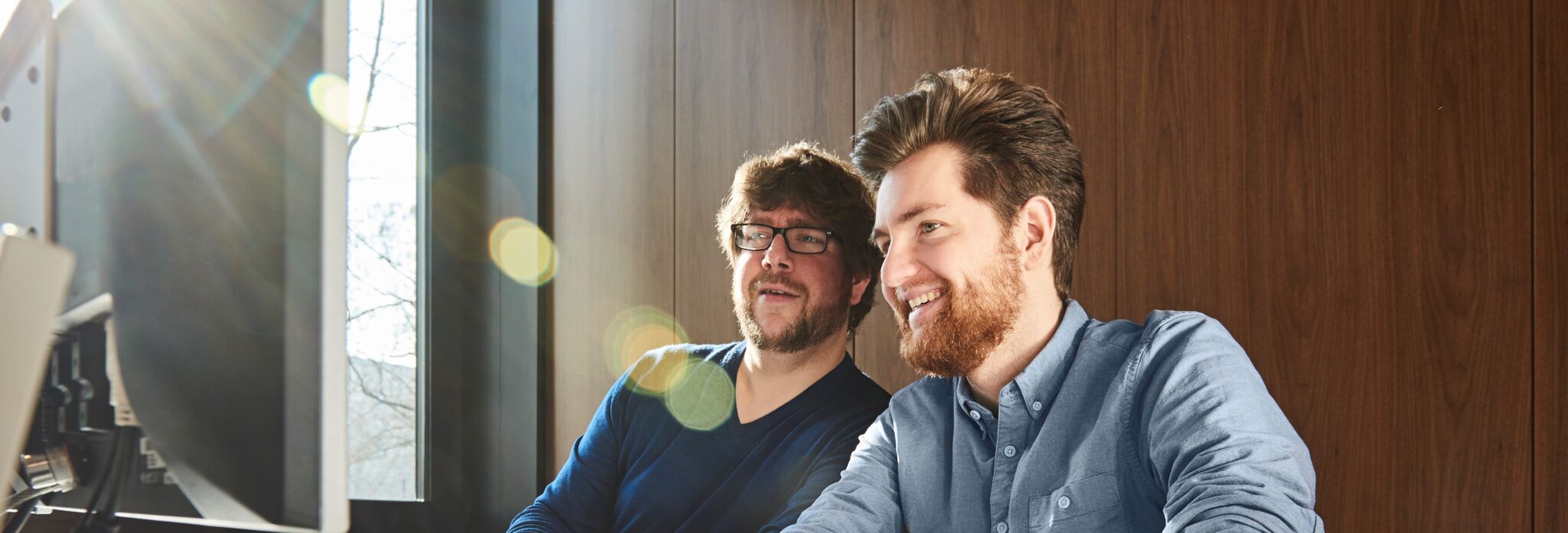 ABL Auf dem Bild sind zwei Männer zu sehen, die auf einen Bildschirm schauen.